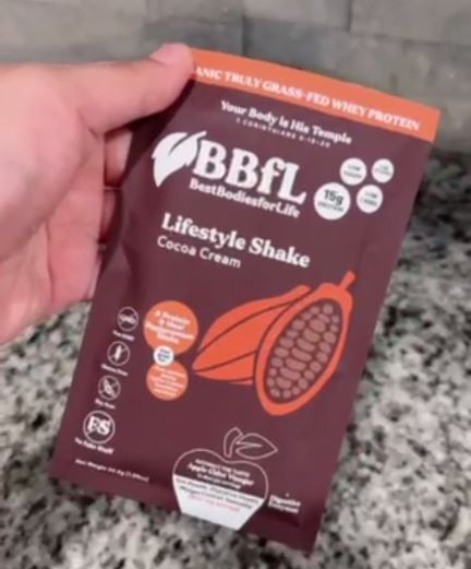 Hand holding a BBFL Lifestyle Shake Cocoa Cream packet