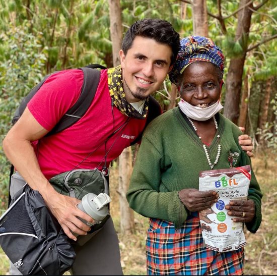 Raul and an elderly woman smiling outdoors, holding a BBFL protein bag