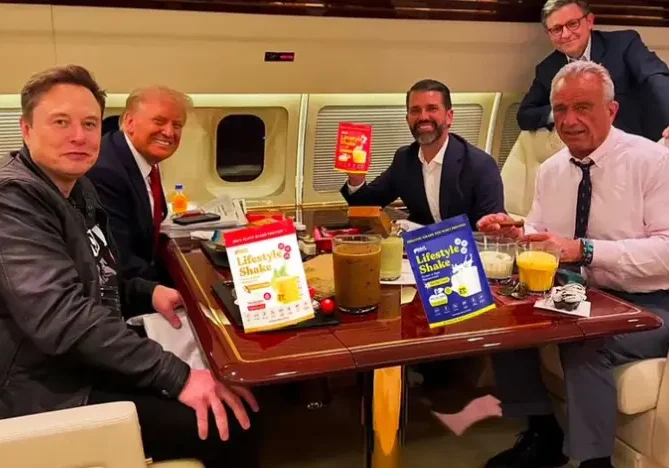 Elon Musk, Donald Trump, Donald Trump Jr., Robert F. Kennedy Jr., and two other men are seated around a table inside a private jet, with various drinks and "Lifestyle Shake" products on display.