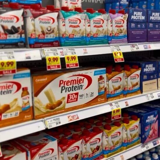 A supermarket aisle shelf filled with various protein drinks, prominently featuring Premier Protein and Pure Protein brands