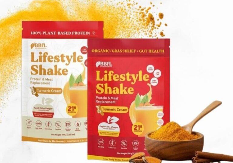 Two packages of BBFL Lifestyle Shake turmeric cream protein powder stand next to a bowl of turmeric powder.